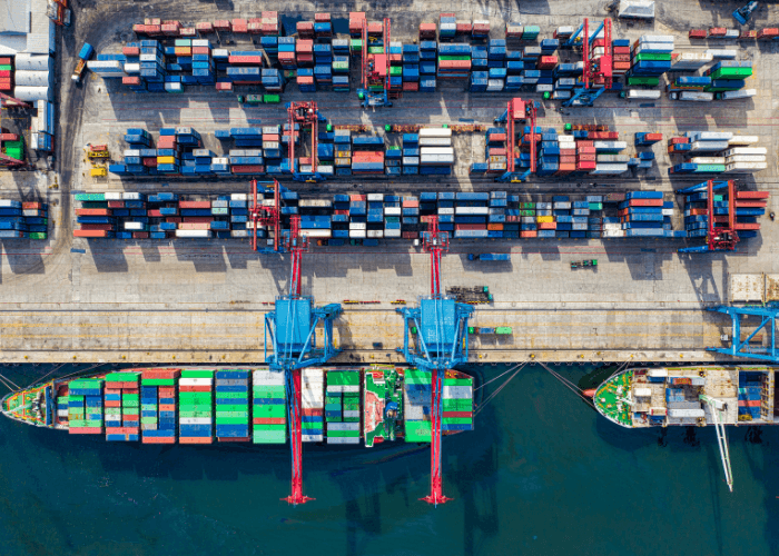 Container ship docked at a port terminal with stacked shipping containers, supporting global import and export operations.